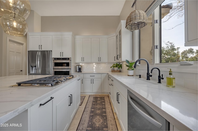 kitchen featuring sink, hanging light fixtures, appliances with stainless steel finishes, white cabinets, and backsplash