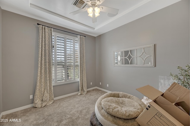 sitting room with ceiling fan, a tray ceiling, and light carpet