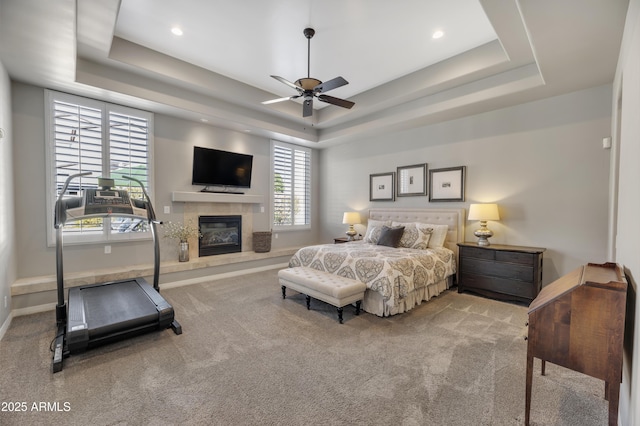 bedroom with ceiling fan, a raised ceiling, and light carpet