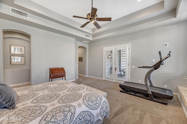 carpeted bedroom with ceiling fan, a tray ceiling, and access to exterior