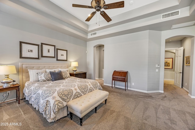 carpeted bedroom with ceiling fan and a tray ceiling