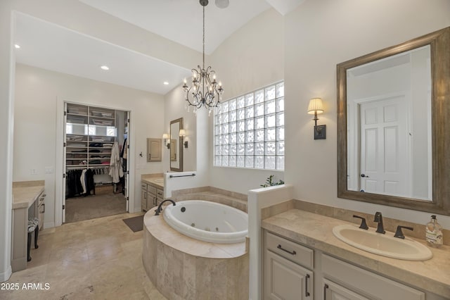 bathroom with vanity, tiled tub, and a notable chandelier