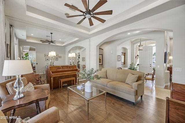 living room with hardwood / wood-style flooring, ceiling fan, and a tray ceiling