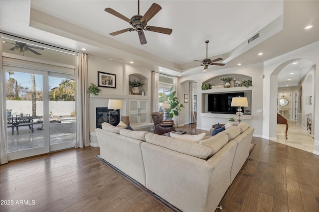 living room with hardwood / wood-style flooring, a wealth of natural light, and a tray ceiling