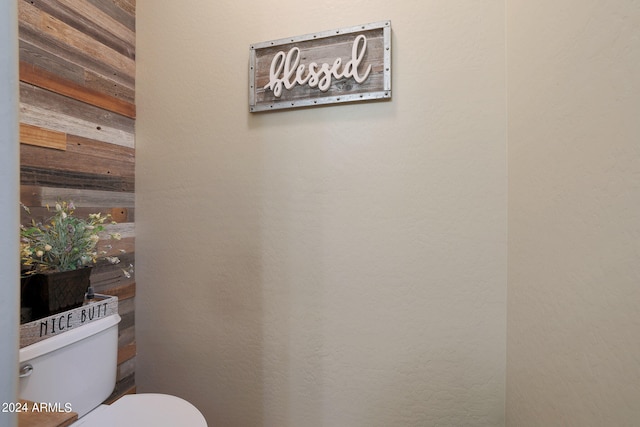 bathroom featuring wood walls and toilet