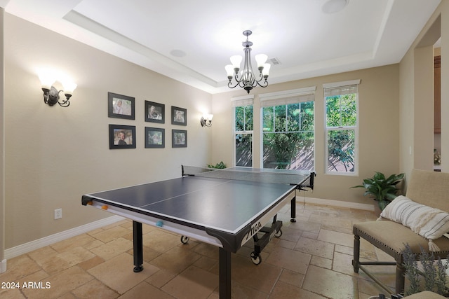 rec room featuring an inviting chandelier and a raised ceiling