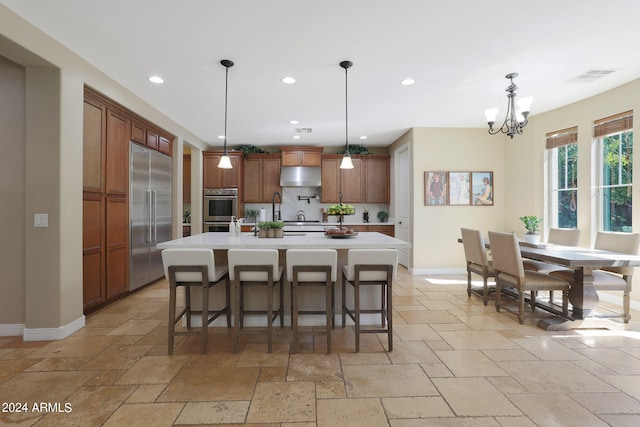 kitchen featuring pendant lighting, an island with sink, appliances with stainless steel finishes, and a breakfast bar