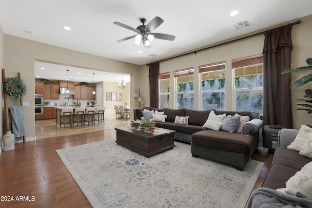 living room with wood-type flooring and ceiling fan with notable chandelier