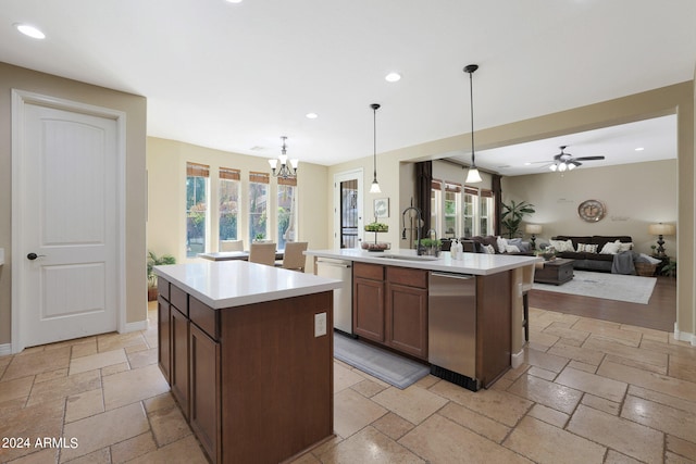 kitchen featuring sink, stainless steel dishwasher, decorative light fixtures, a center island with sink, and ceiling fan with notable chandelier