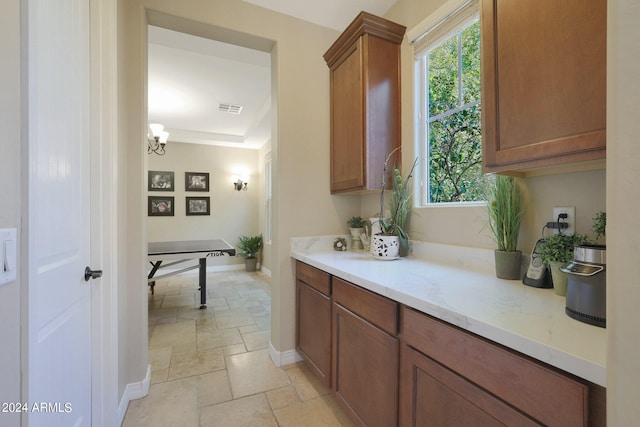 kitchen featuring light stone counters and a notable chandelier