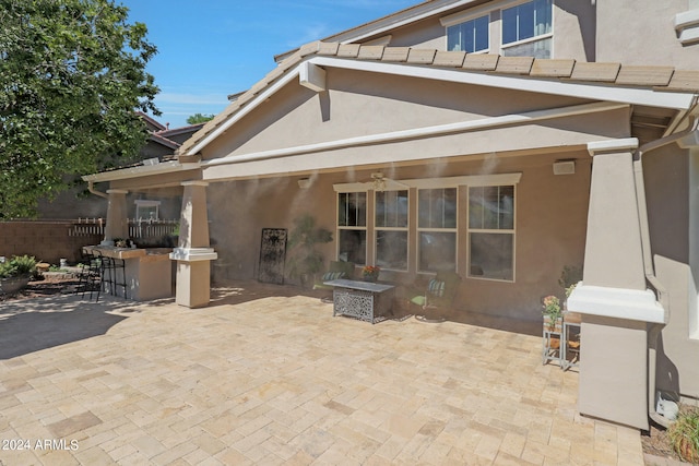 rear view of house featuring ceiling fan, an outdoor bar, and a patio