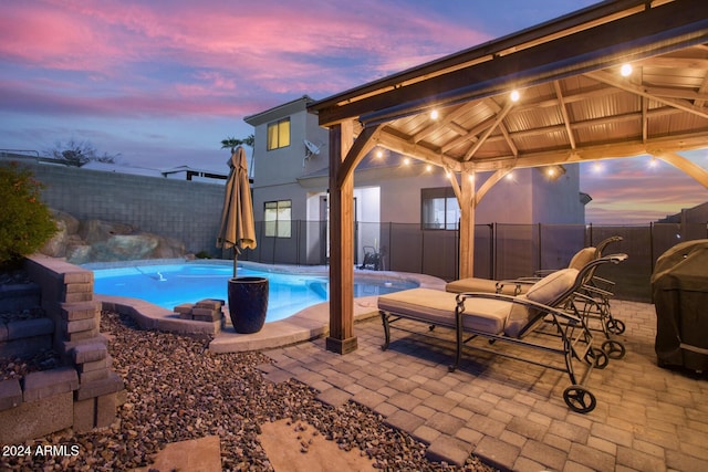 pool at dusk with a gazebo and grilling area