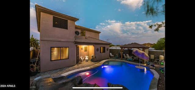 pool at dusk with a gazebo and a patio area