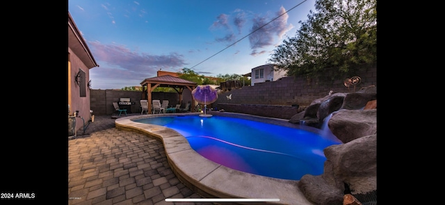 pool at dusk featuring a gazebo and a patio area