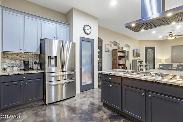 kitchen featuring light stone countertops, ceiling fan, stainless steel appliances, backsplash, and island range hood