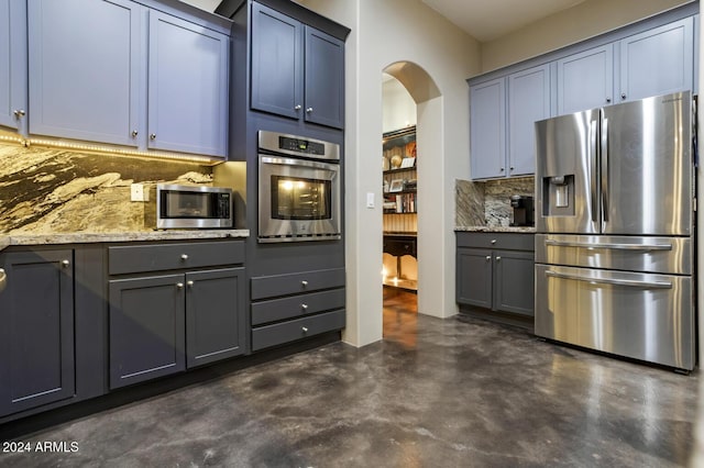 kitchen featuring appliances with stainless steel finishes, backsplash, and light stone counters