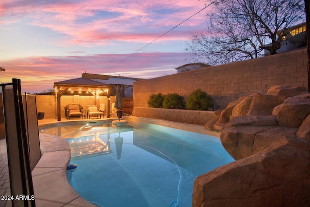 pool at dusk with a gazebo and an outdoor hangout area