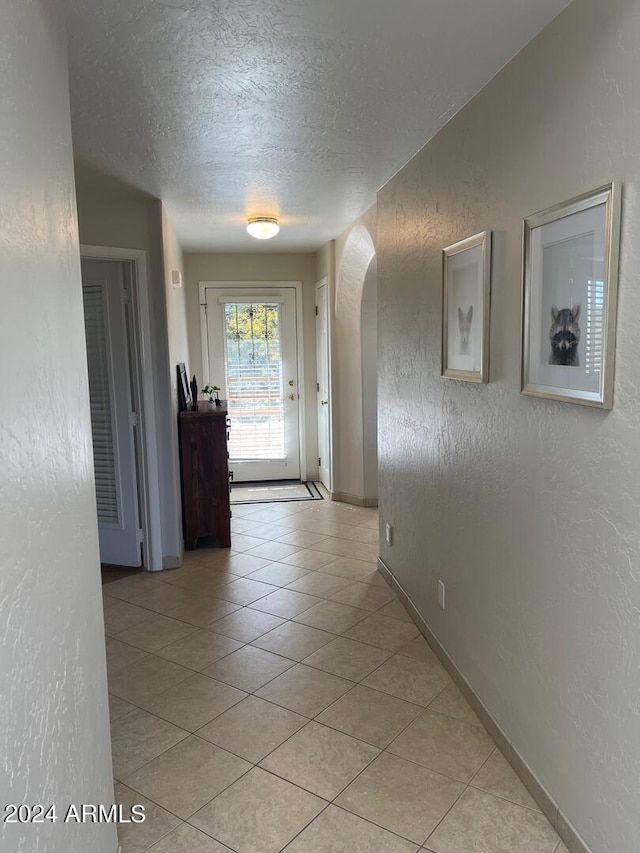 corridor with light tile floors and a textured ceiling