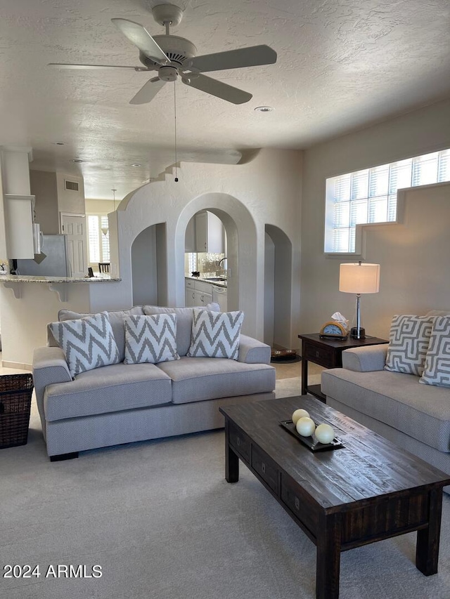 living room with a textured ceiling, a healthy amount of sunlight, and ceiling fan