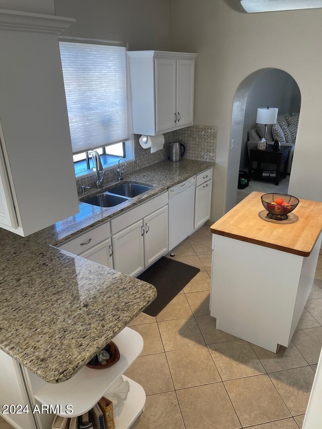 kitchen with light tile floors, dishwasher, sink, white cabinetry, and butcher block countertops