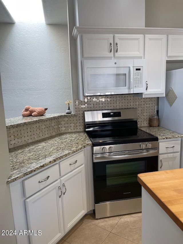 kitchen with tasteful backsplash, white cabinetry, light tile floors, stainless steel electric stove, and light stone countertops