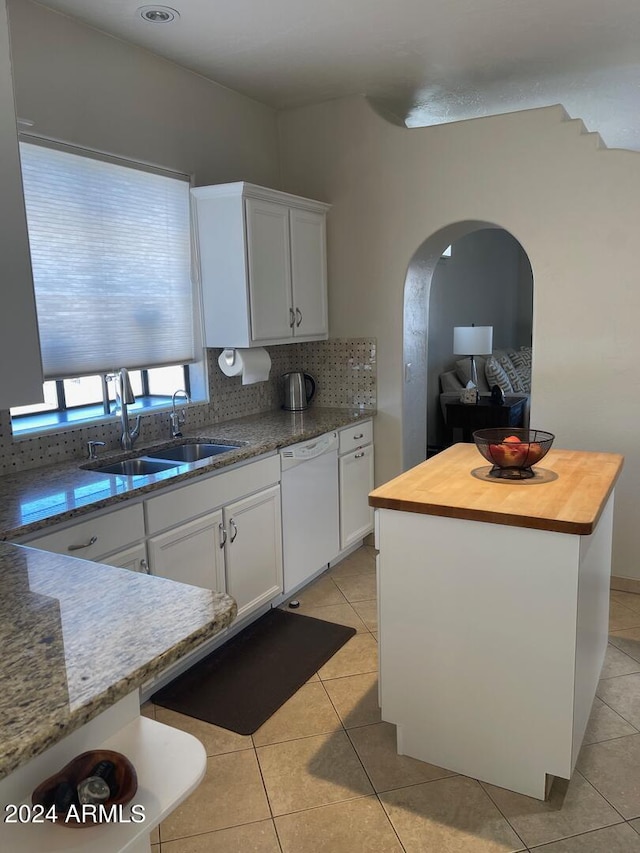 kitchen with white dishwasher, white cabinets, and sink