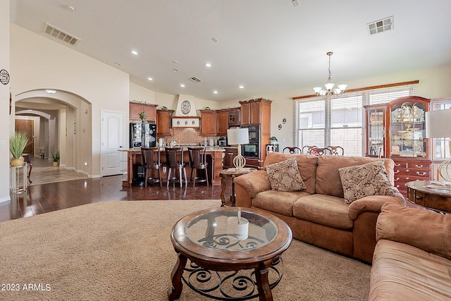 living room with a notable chandelier, dark hardwood / wood-style flooring, and lofted ceiling