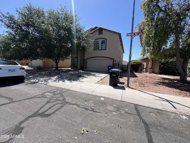 view of front facade featuring a garage, concrete driveway, and stucco siding