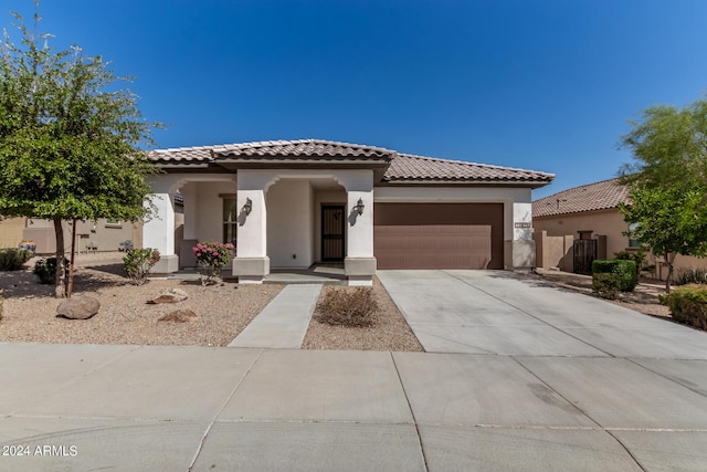 mediterranean / spanish-style house featuring stucco siding, a tile roof, fence, concrete driveway, and a garage