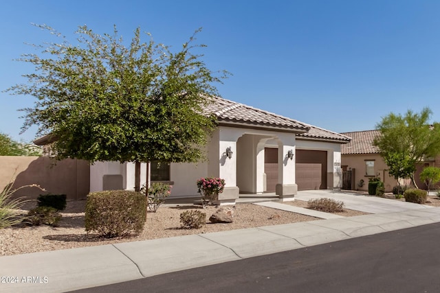 view of front of house featuring a tiled roof, a garage, driveway, and stucco siding