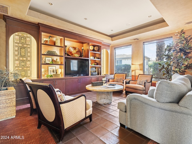 tiled living room with built in shelves and a tray ceiling