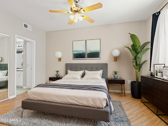 bedroom with ensuite bath, ceiling fan, and light hardwood / wood-style flooring