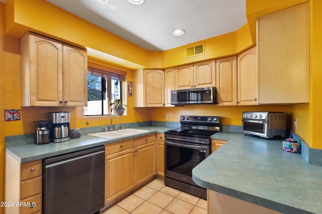 kitchen with light tile patterned floors, light brown cabinetry, sink, and appliances with stainless steel finishes