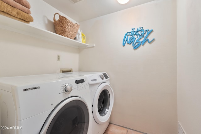 clothes washing area featuring washer and dryer and light tile patterned floors