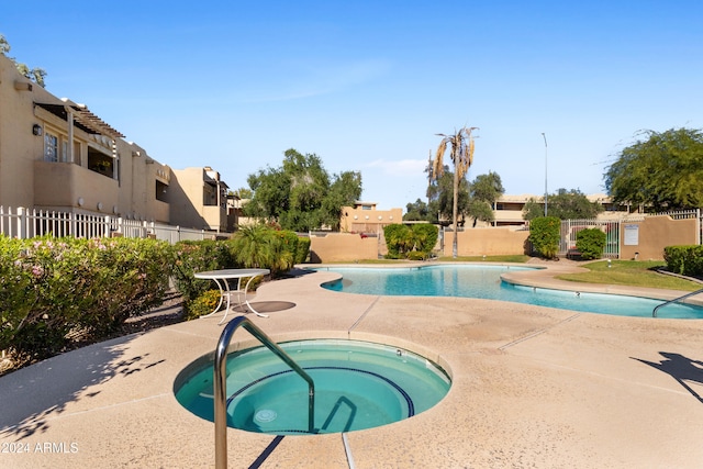 view of swimming pool featuring a hot tub and a patio area