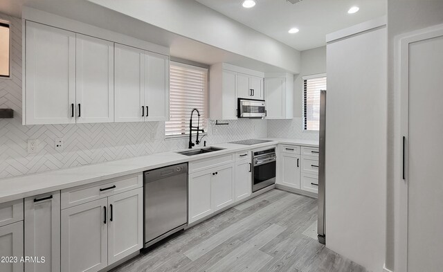9551 E Redfield Rd Unit 1061, Scottsdale, AZ 85260 - kitchen with stainless steel appliances, a sink, light wood-style floors, decorative backsplash, and white cabinetry