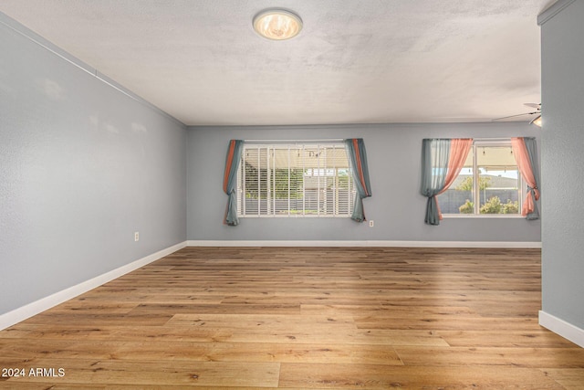 empty room with a textured ceiling and light hardwood / wood-style flooring