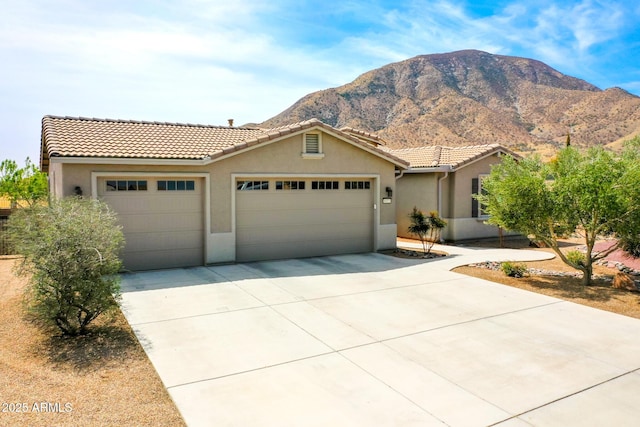 view of front of home with concrete driveway, stucco siding, a tiled roof, a mountain view, and a garage