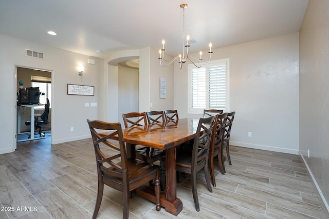 dining room with baseboards, visible vents, light wood-style flooring, and an inviting chandelier