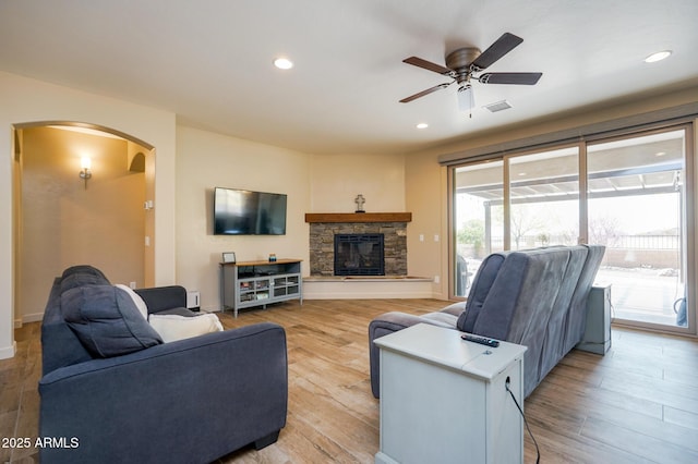 living area with arched walkways, visible vents, a ceiling fan, and light wood finished floors