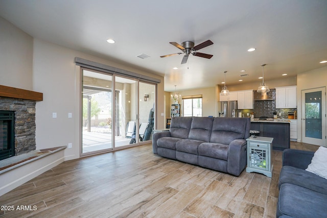 living area featuring recessed lighting, light wood finished floors, visible vents, a ceiling fan, and a fireplace