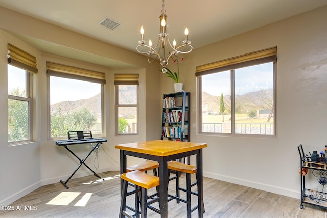 dining room featuring a mountain view, visible vents, a notable chandelier, and light wood finished floors
