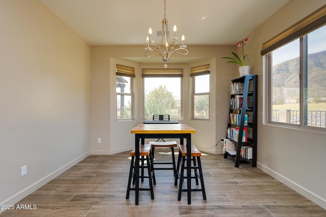 dining area featuring baseboards, light wood-style floors, a mountain view, and an inviting chandelier