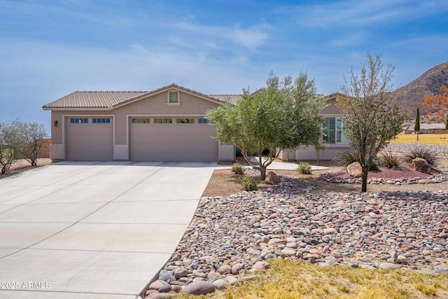 view of front of house featuring a tiled roof, stucco siding, an attached garage, and concrete driveway