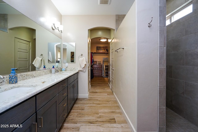 full bathroom featuring double vanity, a sink, baseboards, and wood finished floors