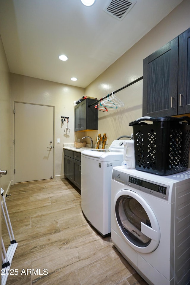 laundry area featuring recessed lighting, light wood finished floors, visible vents, cabinet space, and washer and dryer