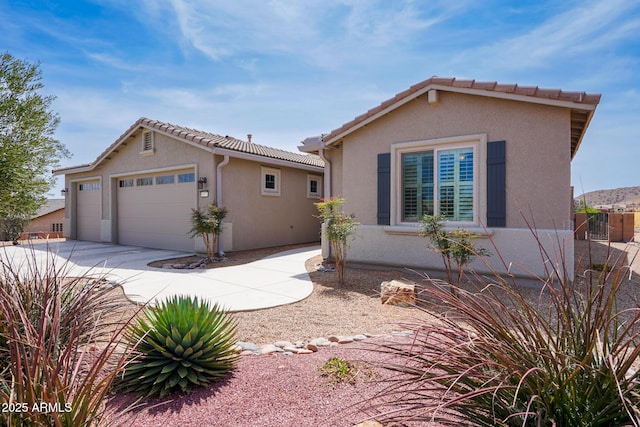 view of front of home with a tiled roof, driveway, stucco siding, and an attached garage
