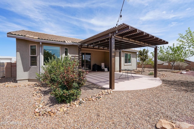 rear view of house featuring a pergola, stucco siding, and fence
