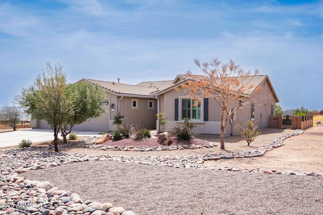 view of front of property with stucco siding, a garage, a tiled roof, and concrete driveway