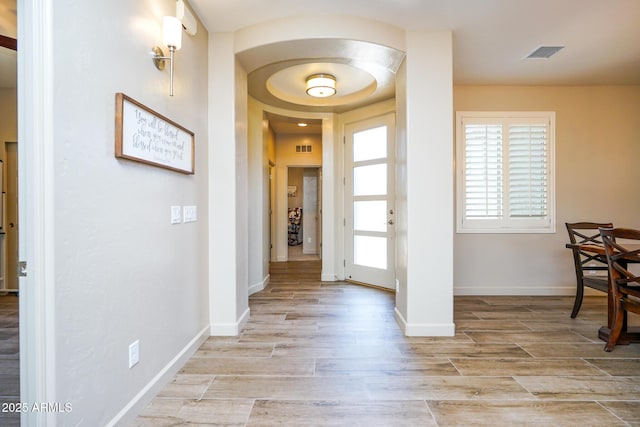 hall with light wood finished floors, baseboards, and visible vents